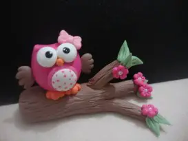 Coruja de biscuit com laço rosa em um galho de árvore